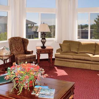 A cozy living room with a sofa, armchair, and coffee table adorned with flowers.