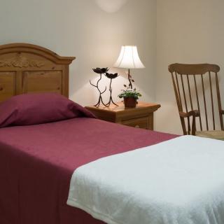 A cozy bedroom with a single bed, nightstand, and rocking chair.