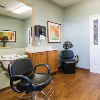 An interior view of a hair salon with chairs, sink, and framed artwork on the walls.