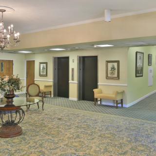 A well-decorated lobby area with elevators, a chandelier, and elegant furnishings.