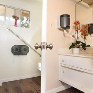 A split-view image of a bathroom, showing both the sink with flowers and a toilet area.