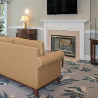 A cozy living room featuring a beige sofa, a fireplace with a TV above it, and elegant decor.