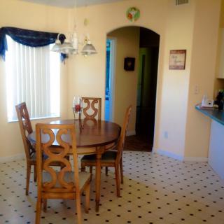 A bright dining area with a round wooden table and four chairs on a patterned tiled floor.