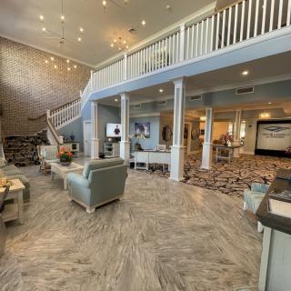 A spacious and modern lobby area with elegant furniture, chandeliers, and grand staircase.
