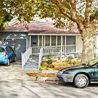A suburban house with two cars parked in the driveway, surrounded by trees.
