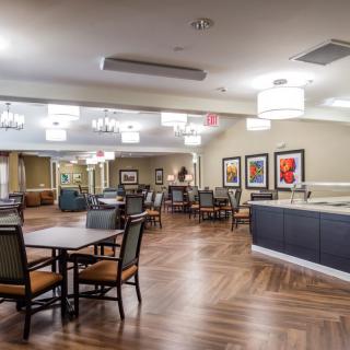 A modern dining area with neatly arranged tables and chairs, adorned with elegant lighting and artwork on the walls.