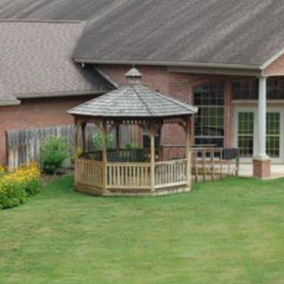 A backyard view featuring a gazebo positioned on a well-maintained lawn next to a house.