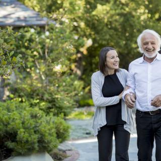 An elderly couple enjoying a walk together in a lush garden.