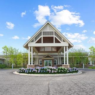 A large building entrance with landscaped flower beds and a clear sky overhead.