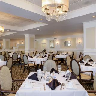 An elegant dining area with neatly arranged tables and chandeliers.
