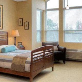 A cozy bedroom with a bed, chair, and large windows.