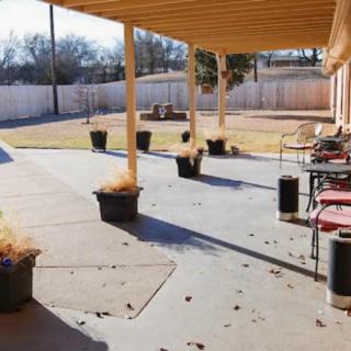 A spacious backyard patio with potted plants and outdoor furniture under a pergola.