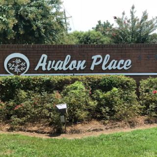 Entrance sign for Avalon Place, a neighborhood surrounded by greenery.