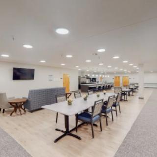 A modern dining area with tables, chairs, and a television mounted on the wall.