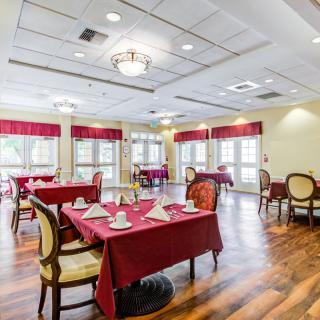 A well-lit dining room with red tablecloths and elegant chairs.