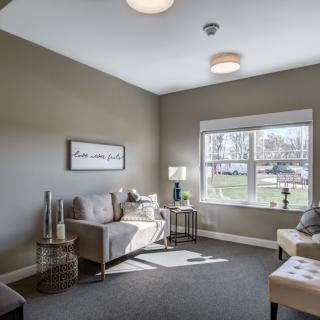 A modern, cozy living room with neutral tones and ample natural light.
