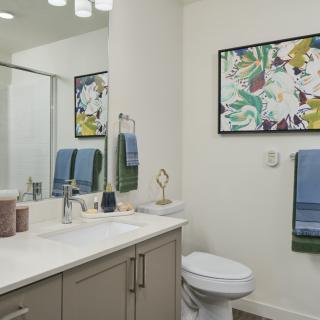 A modern bathroom featuring a sink, toilet, and decorative artwork on the wall.