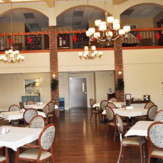 An elegant dining area with neatly arranged tables and chairs, decorated with chandeliers.