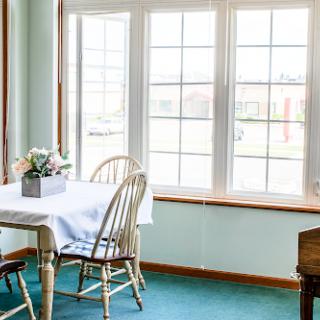 A bright and inviting dining area with a table and chairs, framed by large windows that let in ample sunlight.