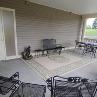 A covered patio with outdoor furniture, including metal chairs and a table on an area rug.