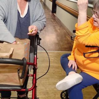 Two people interacting in a hallway, one using a walker.