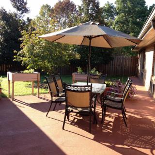 A sunny backyard patio with a table, chairs, and an umbrella.