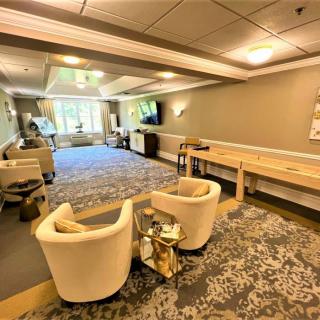 A modern lounge space with comfortable seating and a shuffleboard table.