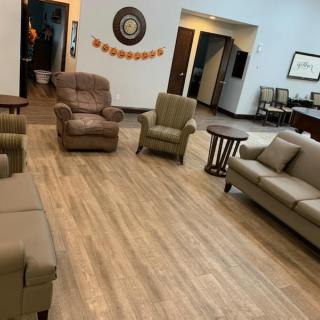 A comfortable waiting room with various seating options and tables, featuring neutral decor.
