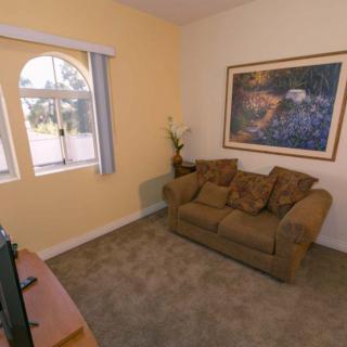 A cozy living room with a sofa, artwork on the wall, and a window bringing in natural light.