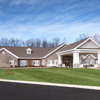 A large, modern house with a well-maintained lawn under a clear blue sky.
