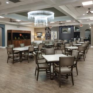 A modern dining area with tables and chairs, featuring a stylish chandelier.