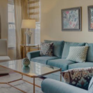 A cozy living room featuring a blue sofa, glass coffee table, and elegant decor.