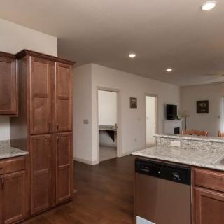 A modern kitchen with wooden cabinets and an island counter, featuring stainless steel appliances and recessed lighting.