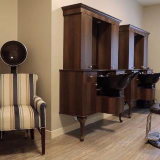 A modern hair salon interior featuring wooden wash stations and a striped dryer chair.