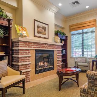 A cozy living room with a brick fireplace, comfortable seating, and bookshelves.