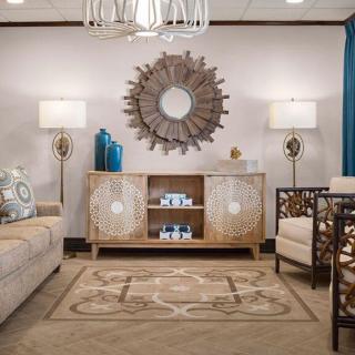 A stylish living room featuring a sunburst mirror, comfortable seating, and elegant decor.