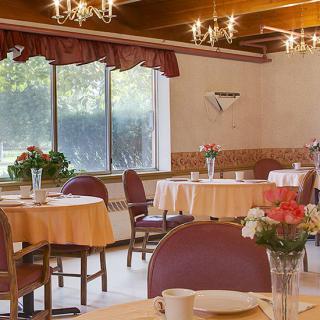 A cozy restaurant dining area with tables set up for guests, featuring elegant chandeliers and floral decorations.
