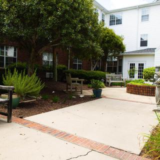 A serene outdoor area with benches and greenery in front of a building.