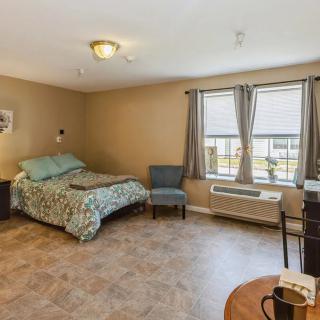 Cozy bedroom with a neatly made bed, a window with curtains, and seating area.