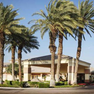A hotel building surrounded by palm trees under a clear blue sky.