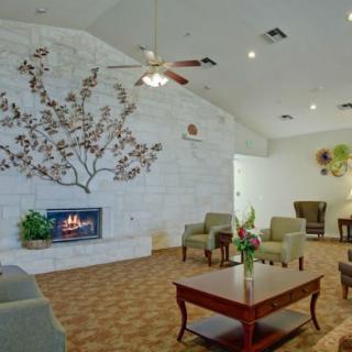 A cozy living room with a fireplace and seating area, featuring decorative wall art.