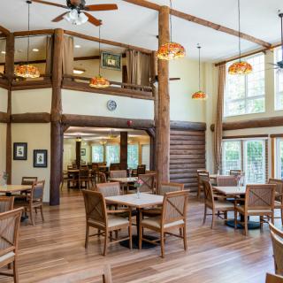 A spacious dining area with a rustic, log cabin style interior featuring wooden tables and high ceilings.