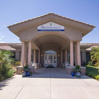 A welcoming entrance to a residential building with columns and landscaping.