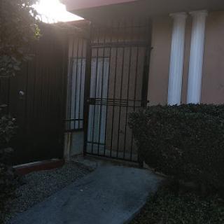 A locked gate leading to a pathway outside a house.