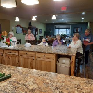 A group of seniors gathered in a spacious kitchen area.