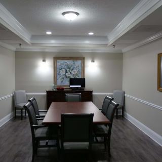 A well-lit conference room with a central table and chairs, decorated with artwork on the wall.