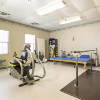 A rehabilitation gym with various exercise equipment and therapy tools.