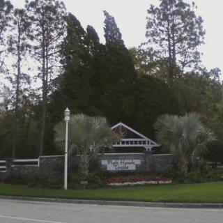 Entrance sign surrounded by trees and greenery.