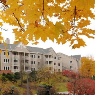 A residential apartment building surrounded by vibrant autumn foliage.