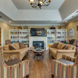 A cozy living room with comfortable sofas, bookshelves filled with books, and a fireplace under a mounted television.